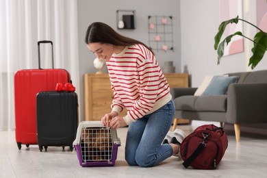 Photo of Smiling woman closing carrier with her pet before travelling indoors