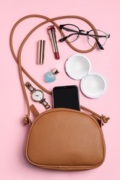 Stylish woman's bag with smartphone and accessories on pink background, flat lay