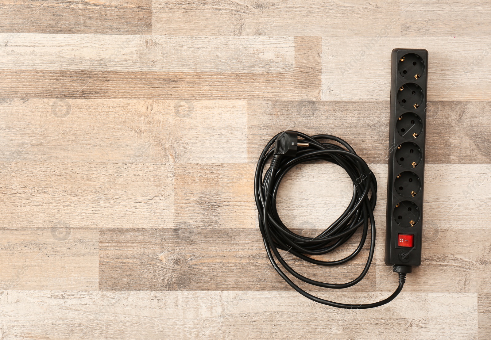 Photo of Extension cord on wooden floor, top view with space for text. Electrician's equipment