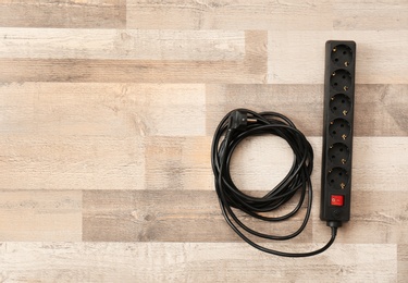 Extension cord on wooden floor, top view with space for text. Electrician's equipment