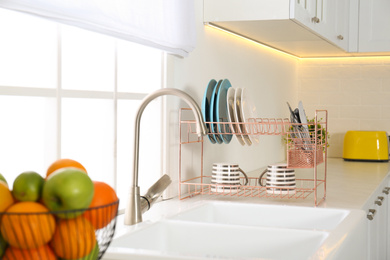 Clean dishes on drying rack in modern kitchen interior