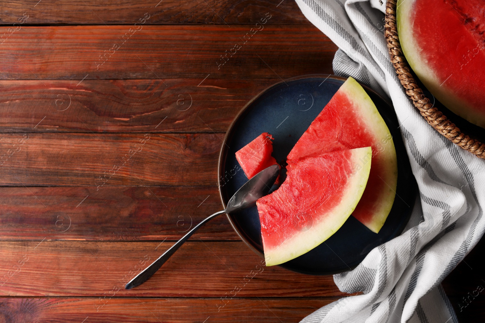 Photo of Sliced fresh juicy watermelon and spoon on wooden table, flat lay. Space for text