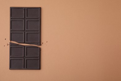 Photo of Broken chocolate bar on brown background, top view. Space for text