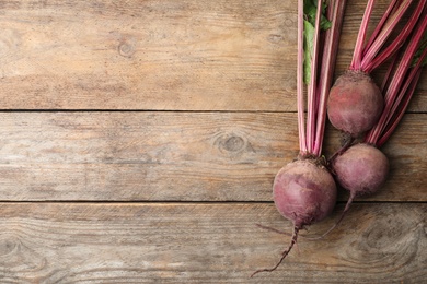 Photo of Raw ripe beets on wooden table, flat lay. Space for text