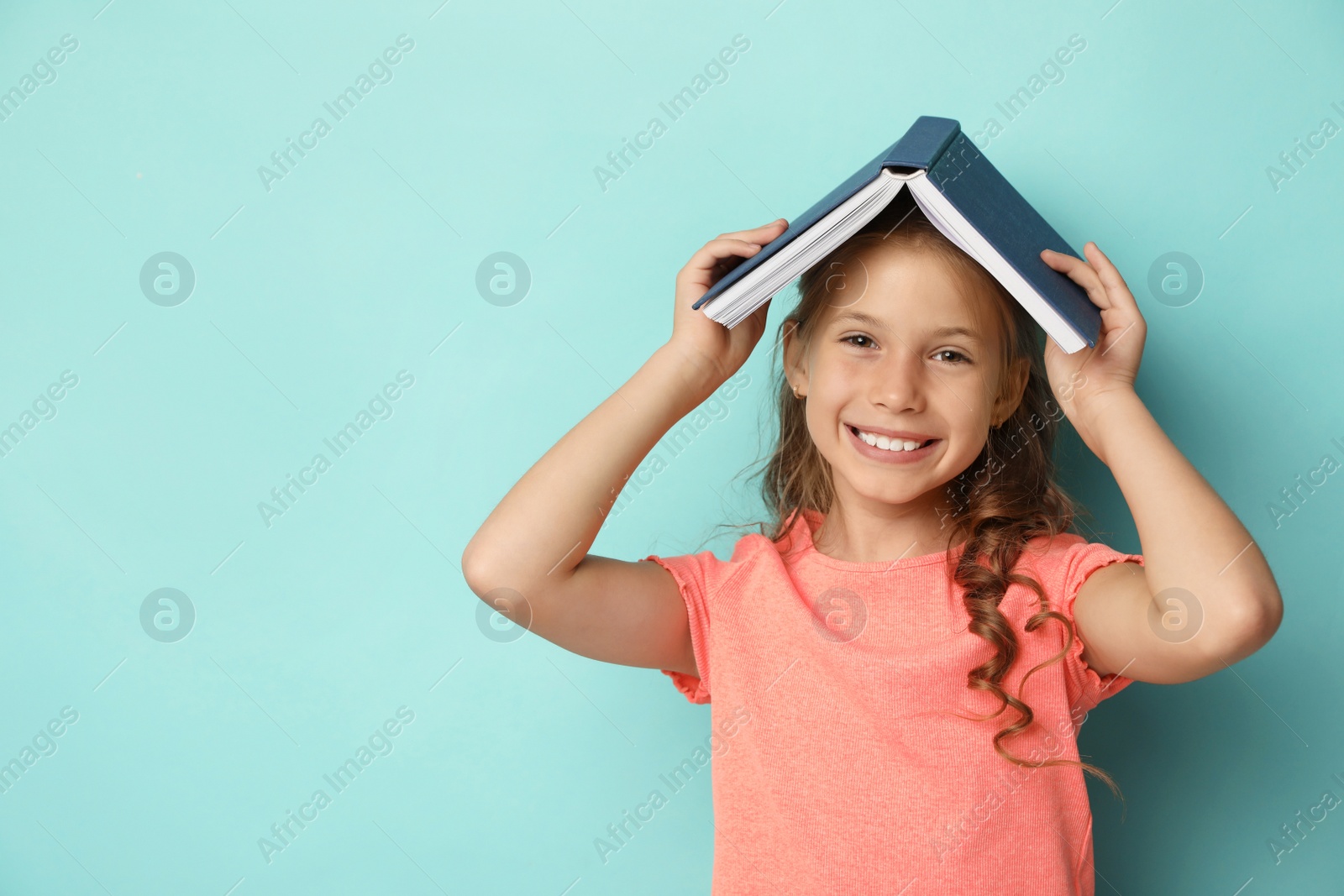 Photo of Portrait of cute girl with book on turquoise background, space for text. Reading concept