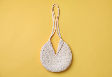 Photo of Stylish straw bag on yellow background, top view. Summer accessory