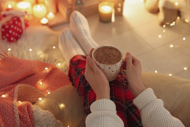 Photo of Woman with cup of hot drink at home, closeup. Christmas celebration