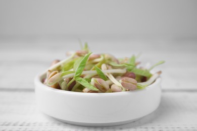 Photo of Mung bean sprouts in bowl on white wooden table, closeup