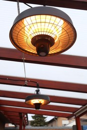 Photo of Stylish hanging infrared heaters on terrace indoors