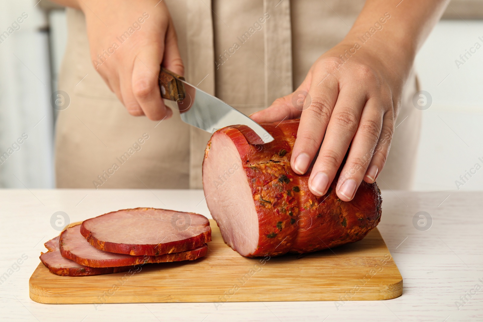 Photo of Woman cutting ham at table in kitchen, closeup