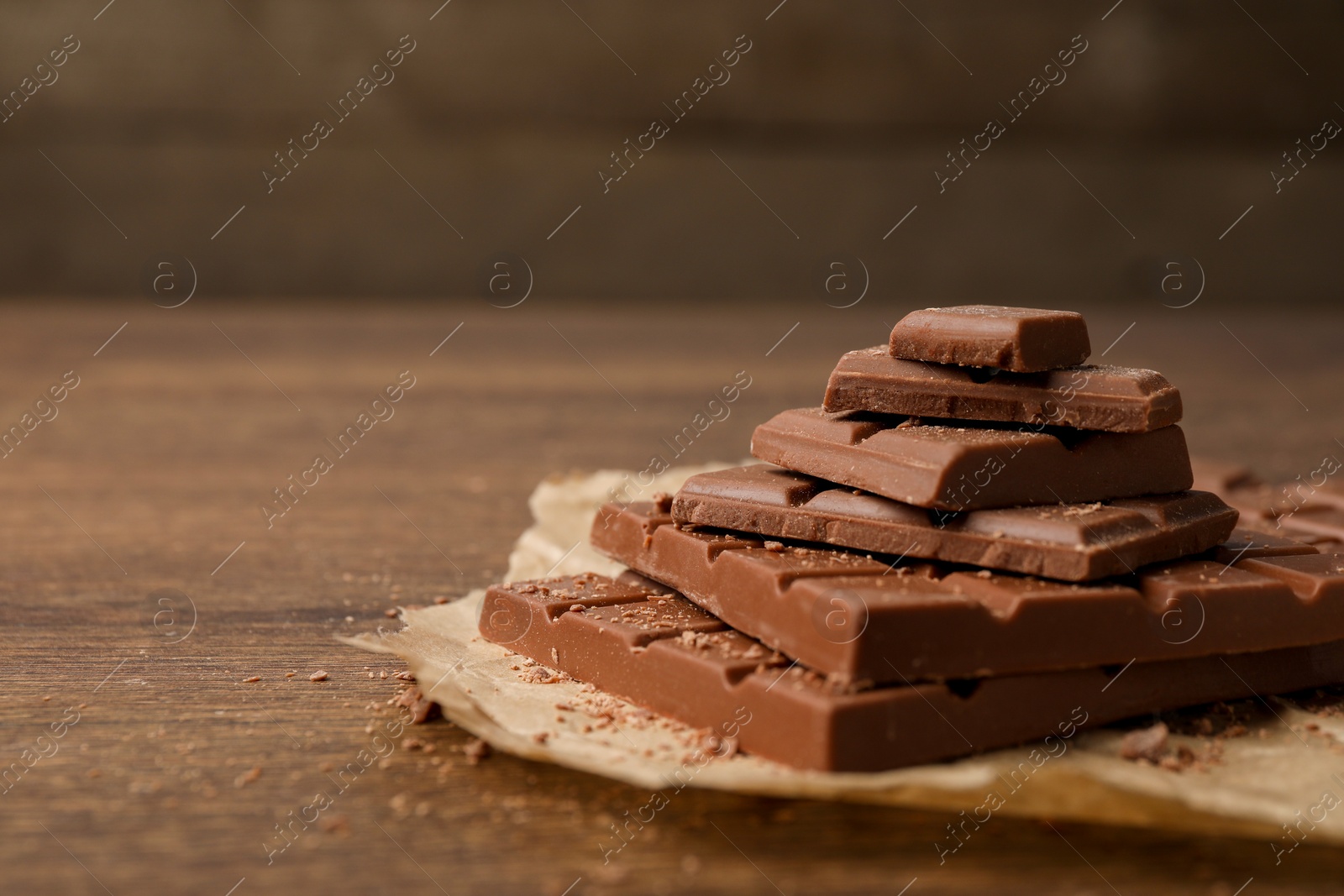 Photo of Pieces and crumbs of tasty chocolate bars on wooden table. Space for text