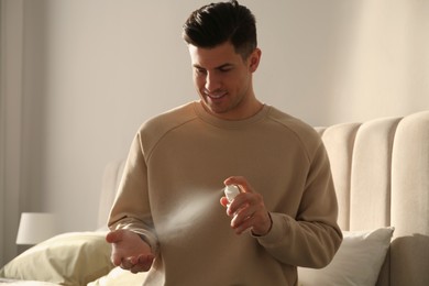 Photo of Man applying spray sanitizer onto hand at home