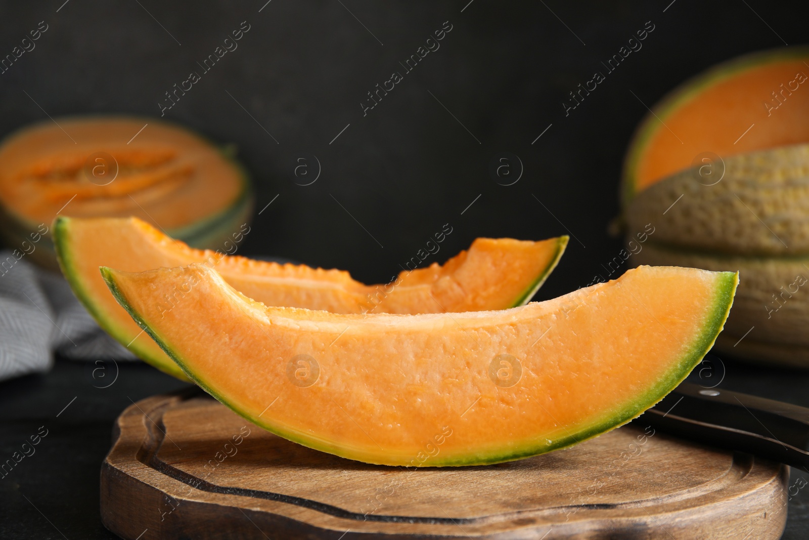 Photo of Slices of tasty fresh melon on wooden board, closeup