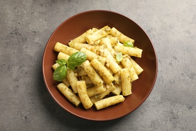 Plate of delicious basil pesto pasta on grey background, top view