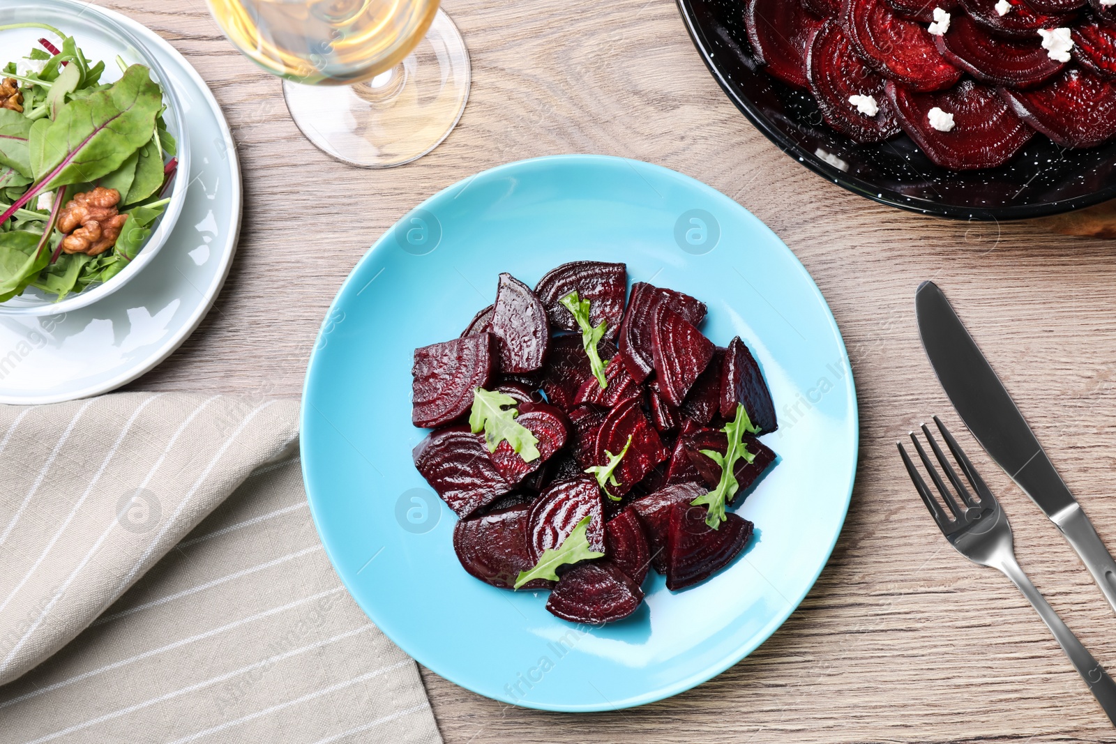 Photo of Roasted beetroot slices with arugula served on wooden table, flat lay