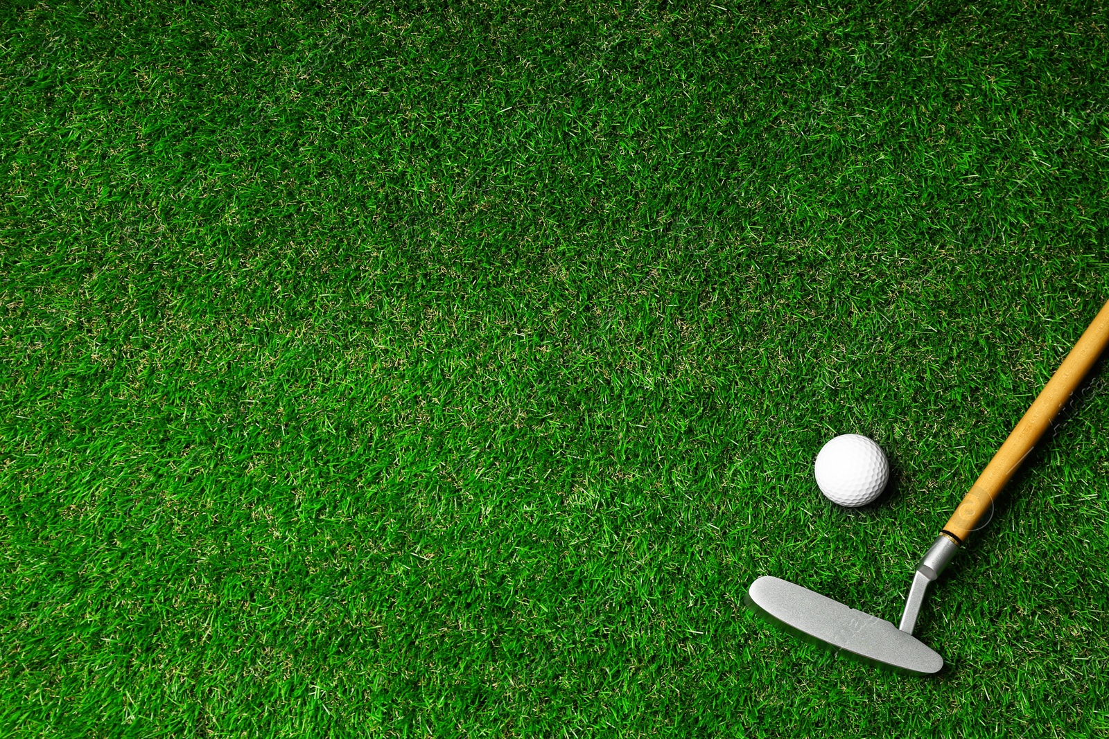 Photo of Golf ball and club on green course, flat lay. Space for text