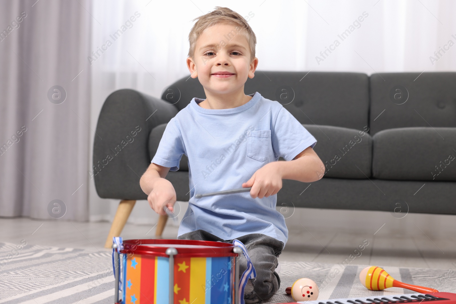 Photo of Little boy playing toy drum at home