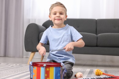 Little boy playing toy drum at home