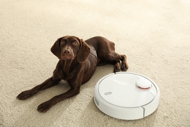 Photo of Modern robotic vacuum cleaner and German Shorthaired Pointer dog on floor indoors