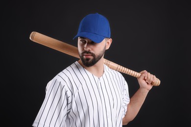 Photo of Man in stylish blue baseball cap holding bat on black background