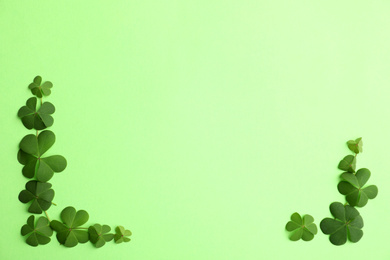 Photo of Clover leaves on green background, flat lay with space for text. St. Patrick's Day symbol