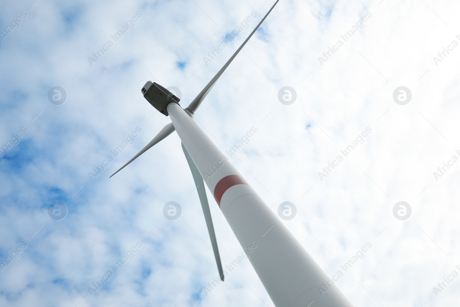 Photo of Wind turbine against cloudy sky, low angle view. Alternative energy source