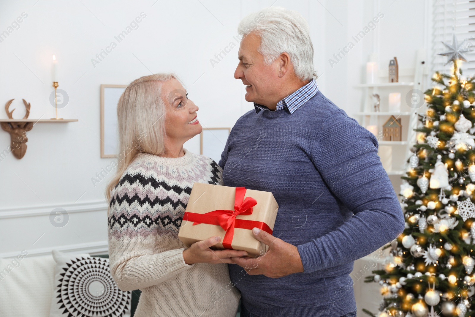 Photo of Happy mature couple with gift box at home. Christmas celebration