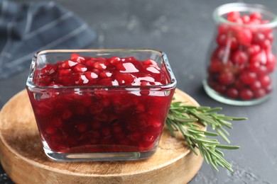 Fresh cranberry sauce and rosemary in glass bowl on gray table, closeup