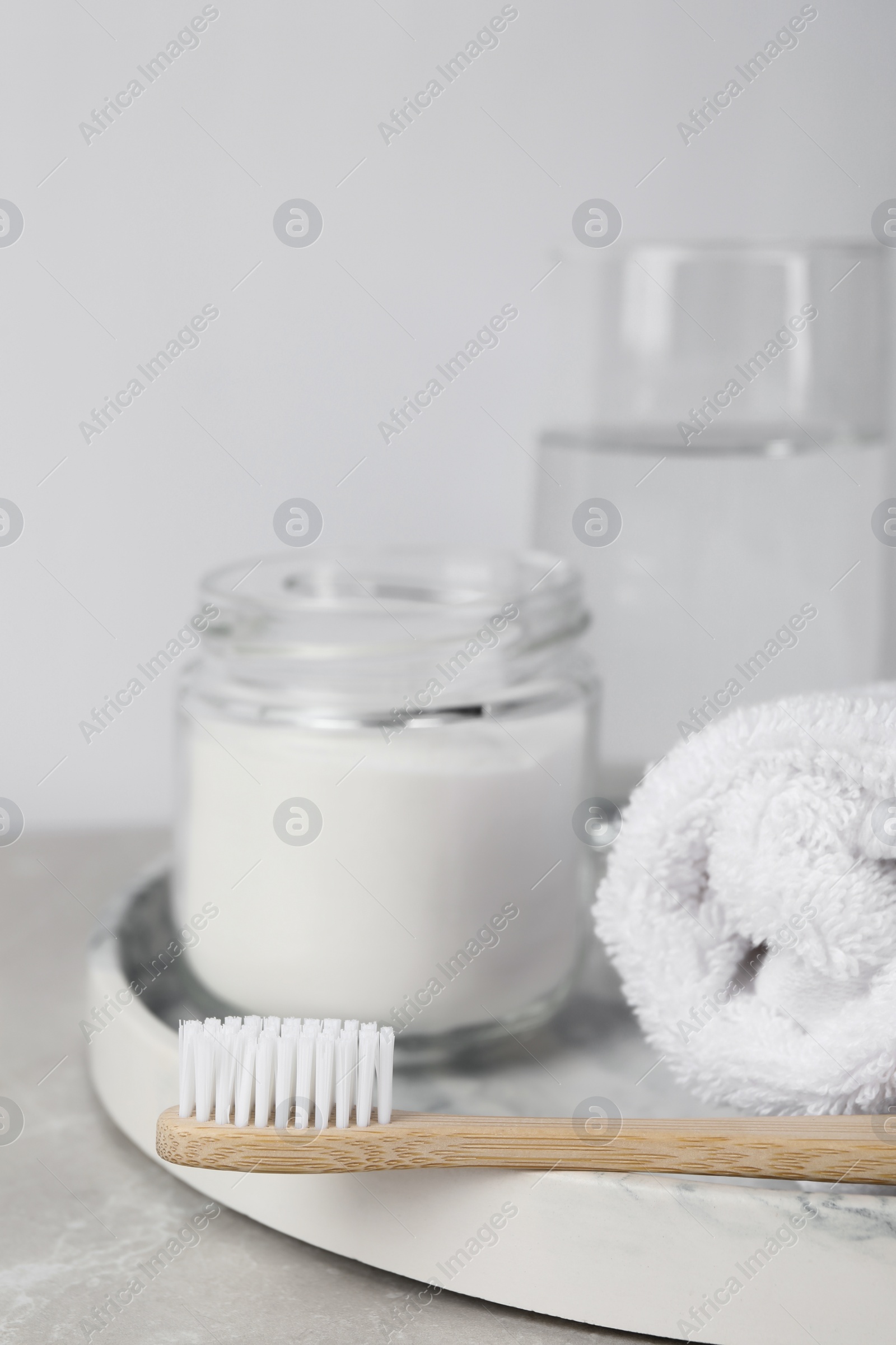 Photo of Bamboo toothbrush, jar of baking soda, towel and glass of water on light table