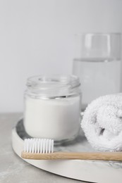 Photo of Bamboo toothbrush, jar of baking soda, towel and glass of water on light table