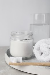 Bamboo toothbrush, jar of baking soda, towel and glass of water on light table