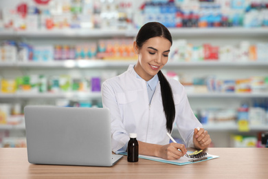 Image of Professional pharmacist working at table in modern drugstore 