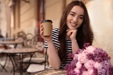 Photo of Beautiful woman with bouquet of spring flowers and coffee in outdoor cafe, space for text