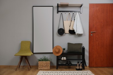 Photo of Modern hallway interior with stylish chair, shoe rack and mirror