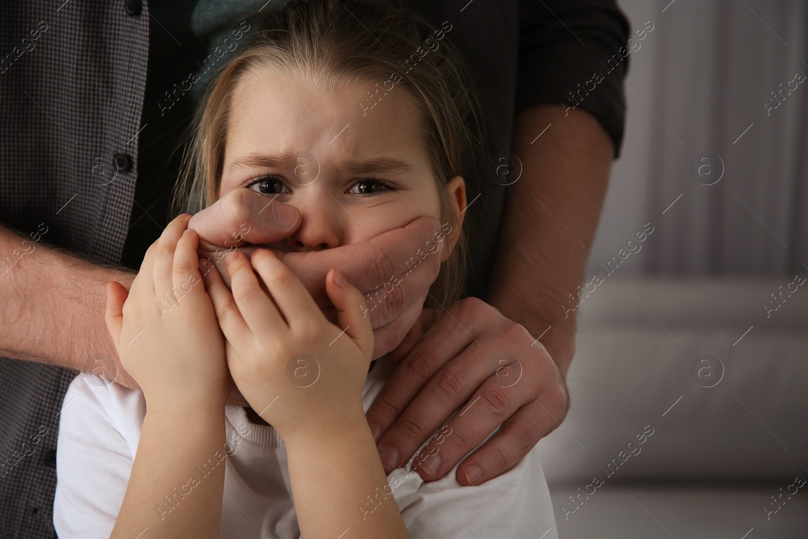 Photo of Man covering scared little girl's mouth indoors. Domestic violence