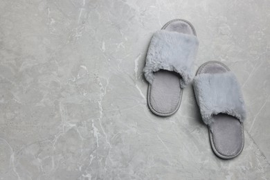 Photo of Pair of soft slippers on grey marble floor, top view. Space for text