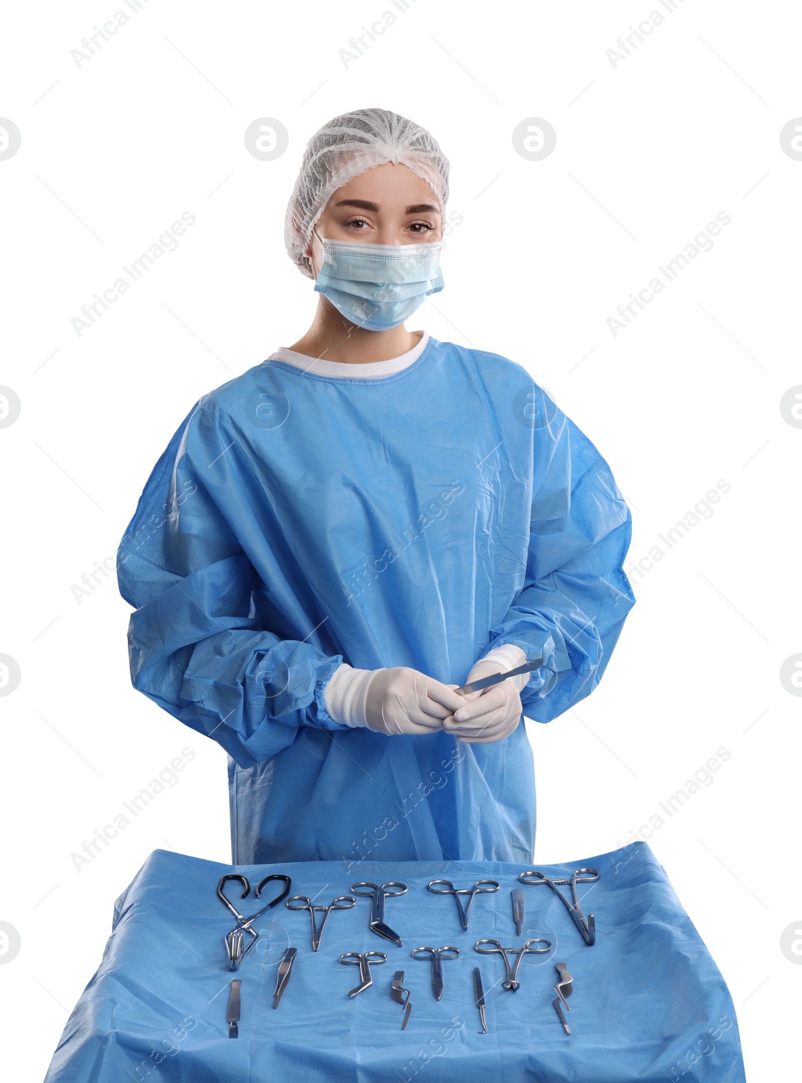 Photo of Doctor holding scalpel near table with different surgical instruments on light background