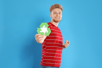 Young man with recycling symbol on blue background