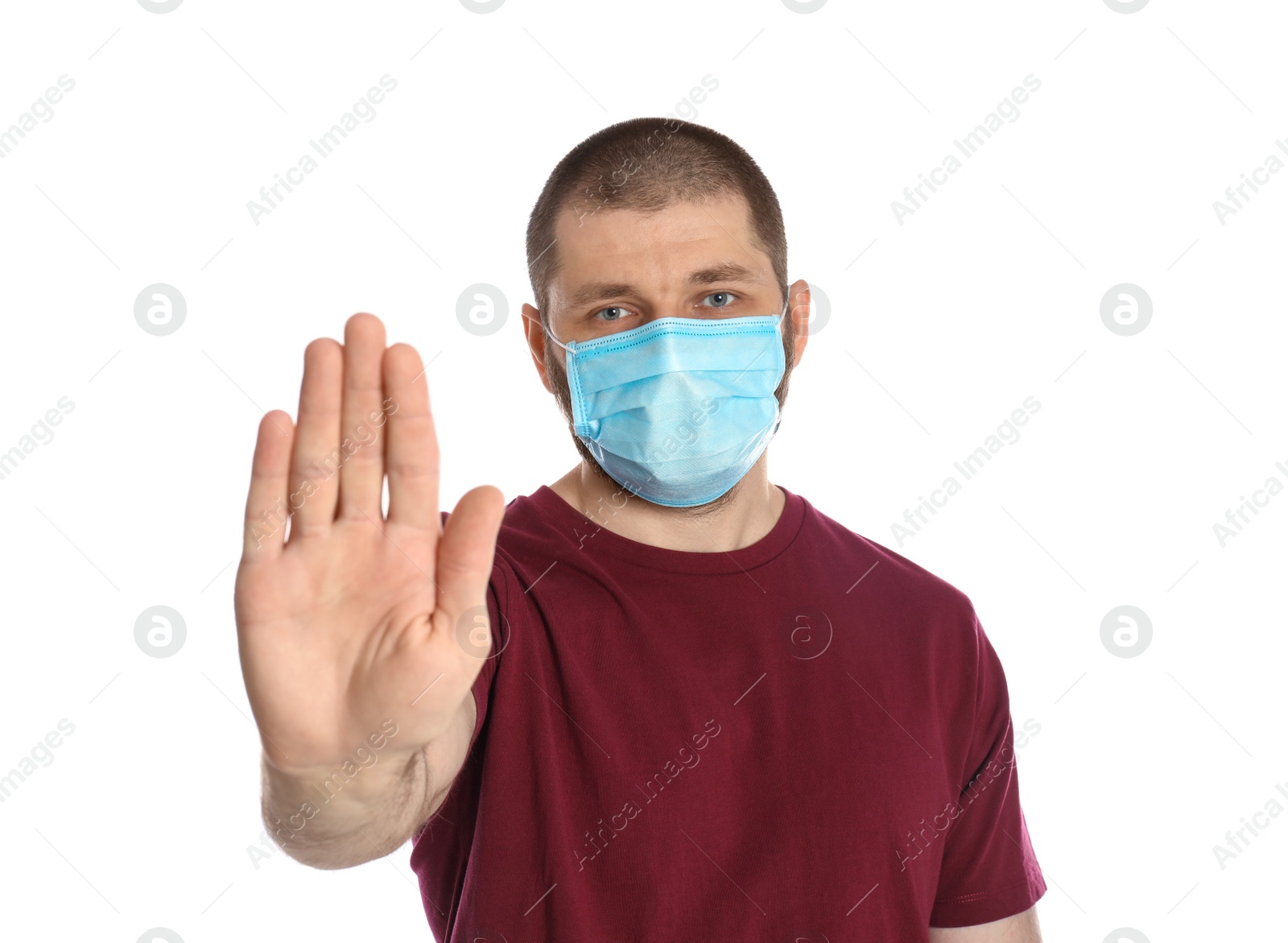 Photo of Man in protective mask showing stop gesture on white background. Prevent spreading of coronavirus