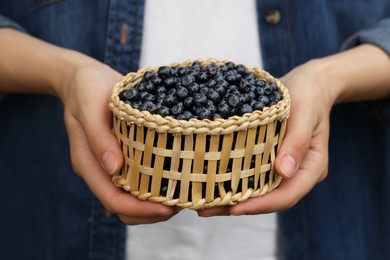 Photo of Woman holding wicker bowl of bilberries, closeup