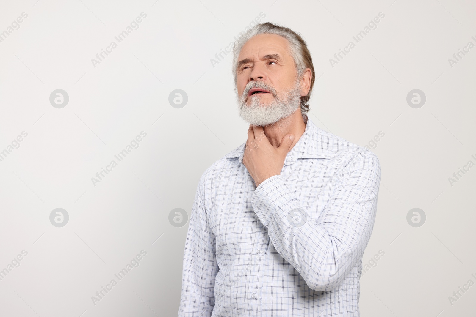 Photo of Senior man suffering from sore throat on white background, space for text. Cold symptoms