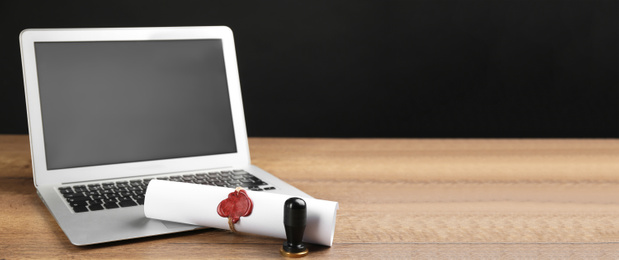 Notary's public pen and sealed document near laptop on wooden table, space for text. Banner design