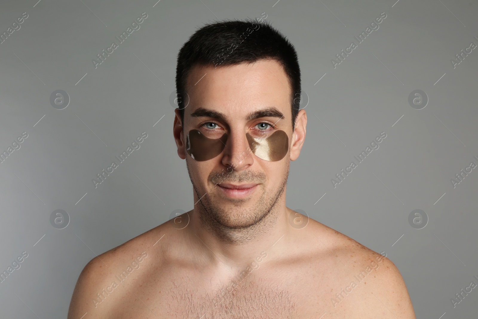 Photo of Young man with under eye patches on grey background