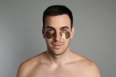 Photo of Young man with under eye patches on grey background