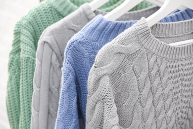 Photo of Collection of warm sweaters hanging on rack, closeup