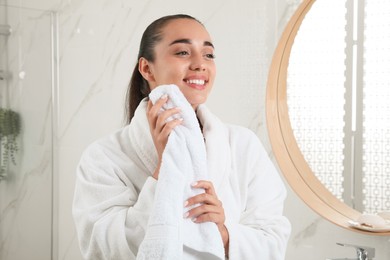 Photo of Beautiful young woman wiping face with towel in bathroom. Facial wash