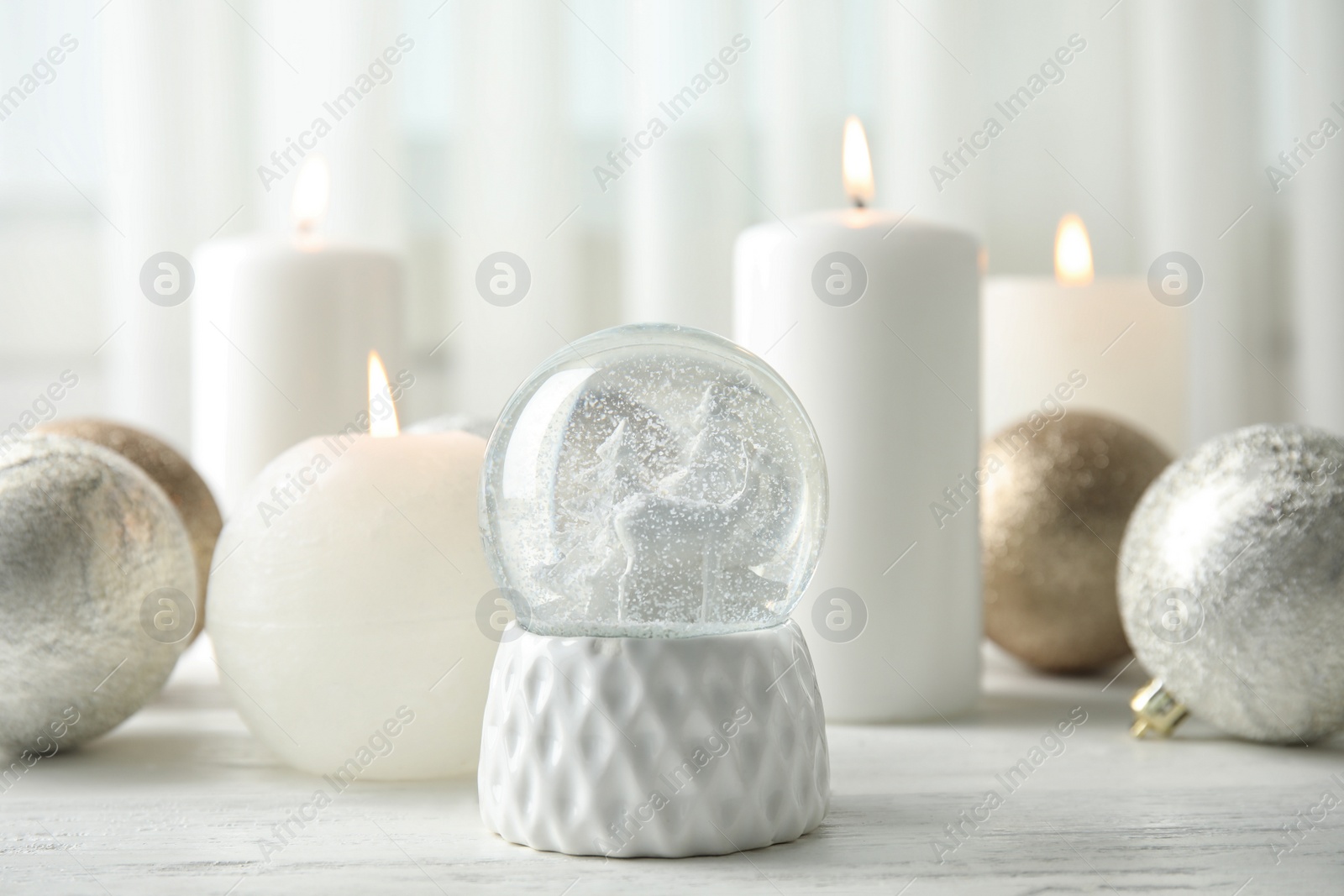 Photo of Snow globe with Christmas balls and candles on table