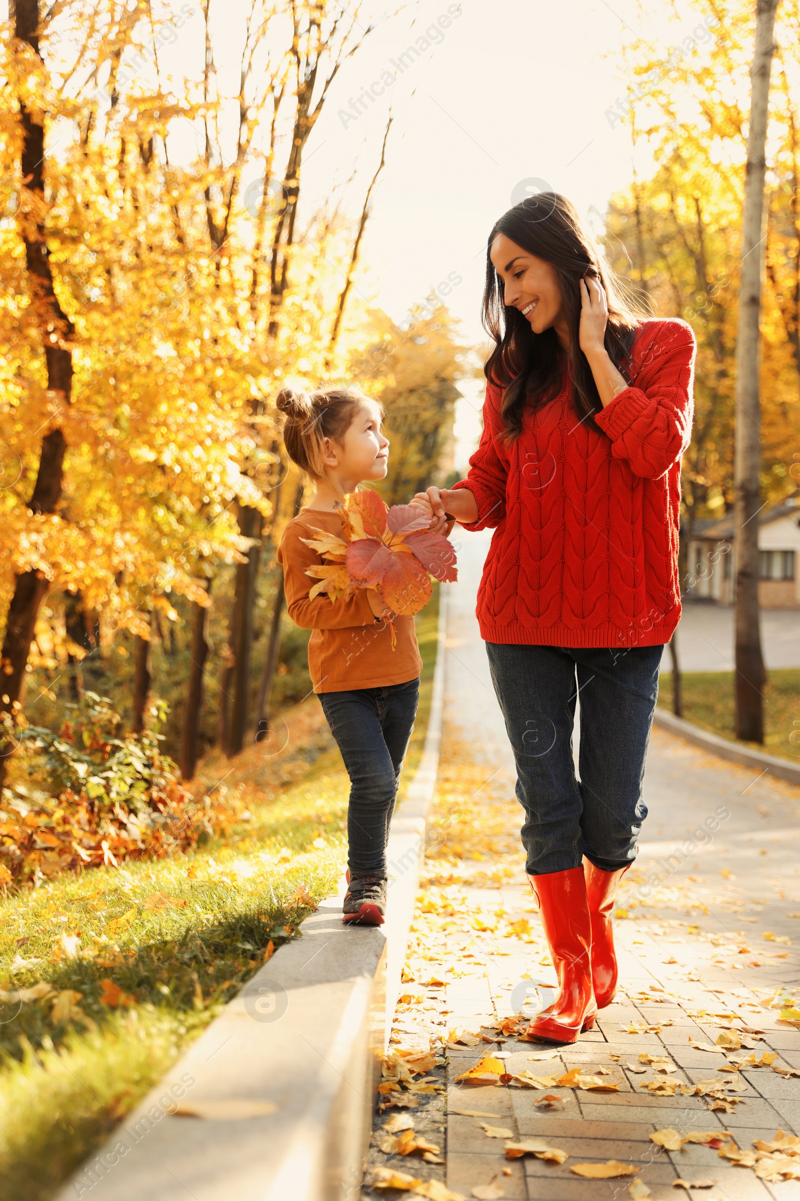 Photo of Happy woman with daughter walking in sunny autumn park