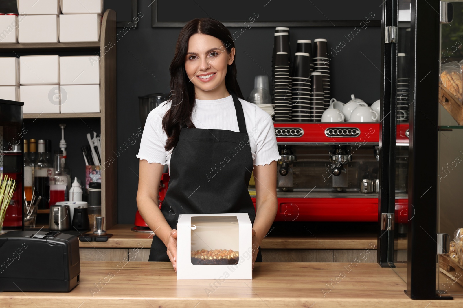 Photo of Business owner in her cafe. Happy woman with delicious cake at desk