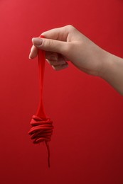 Photo of Woman holding fork with shoelace on red background, closeup